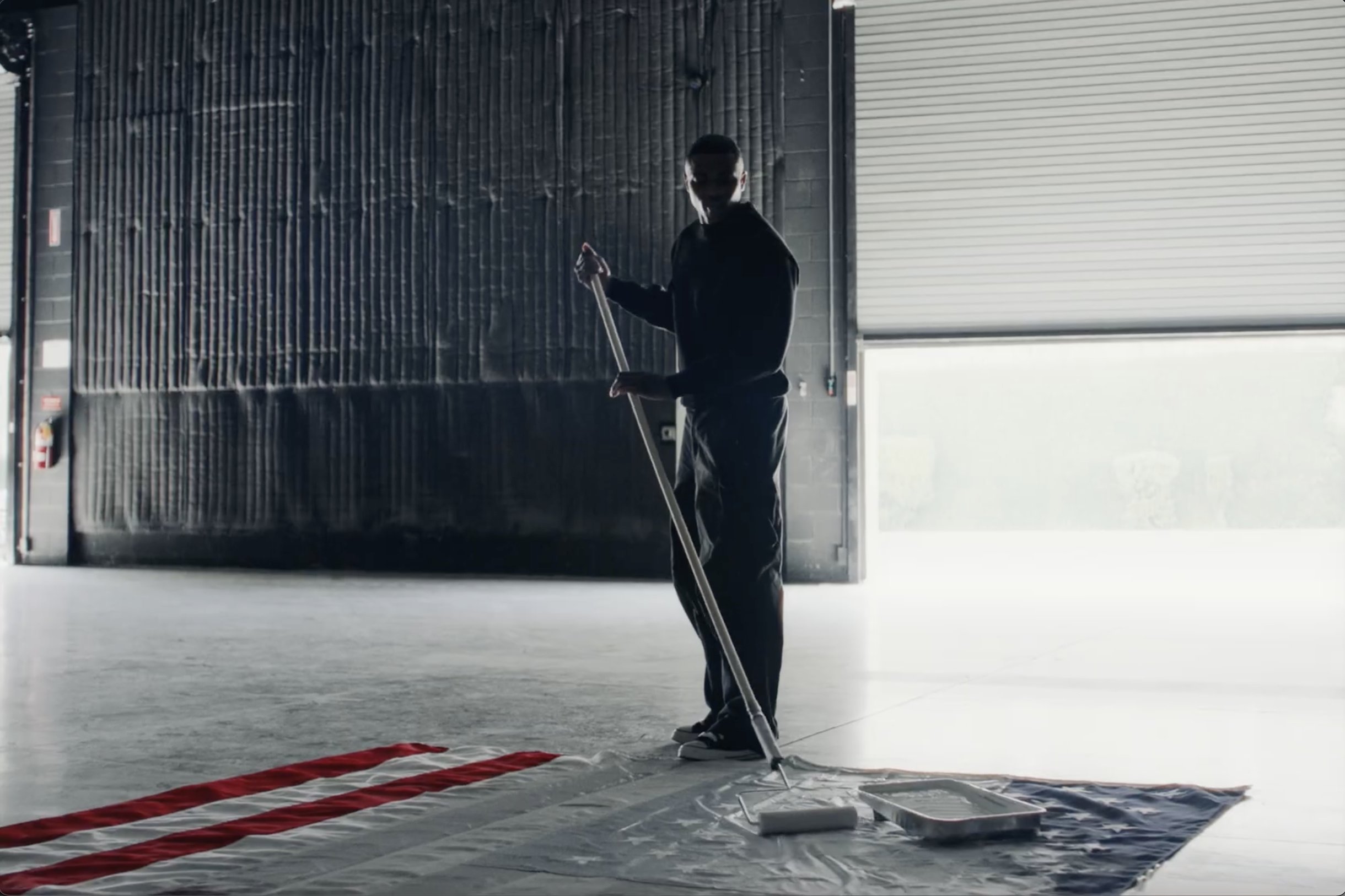 Vince Staples en plein clip de sa chanson White Flag, entrain de peindre le drapeau des etats-unis en blanc